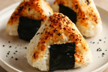 Sült lazacos onigiri, tálalva szezámmaggal és nori algával