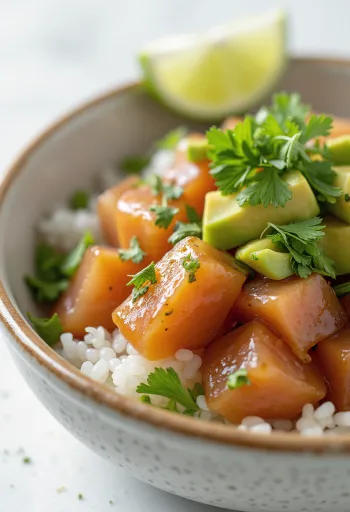 Poké ponzu szósszal friss zöldségekkel és rizságyon, díszítve korianderrel és lime-léval.