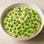 Krémes rizottó zöldborsóval és parmezán sajttal, fehér tányérban tálalva